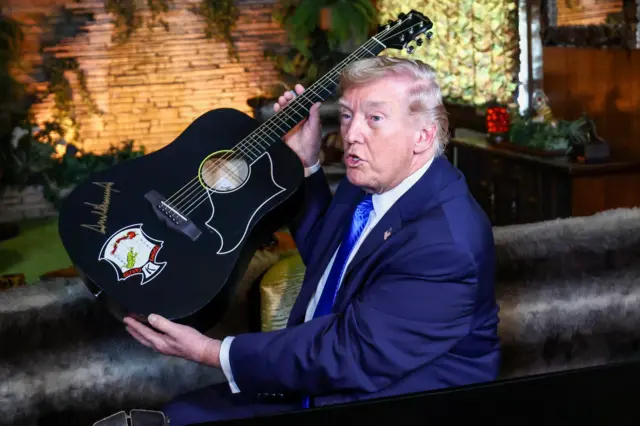 Donald Trump holds a replica of a guitar after signing it during a visit to Graceland