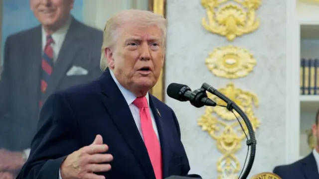 Trump speaking in Oval office in a pink tie.