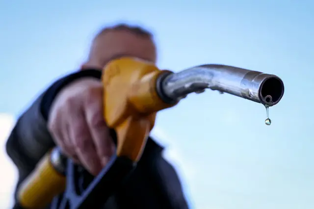 A drop of petrol falls from the nozzle of a petrol pump.