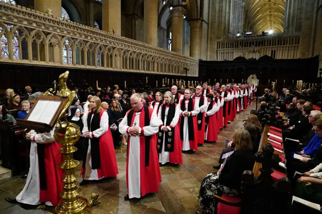 Clergy men and women walk down the centre of Canterbury cathedral