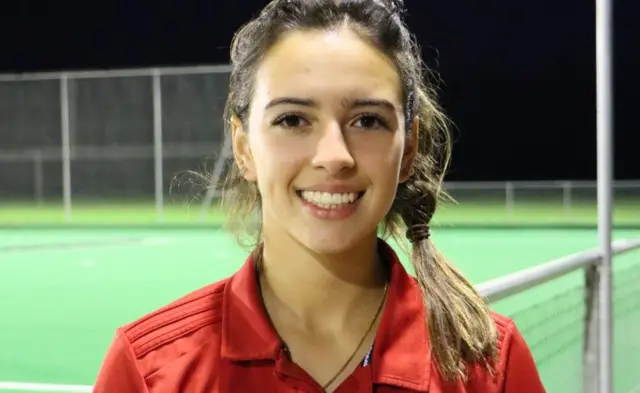 Grace, wearing a red top, smiles at the camera