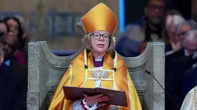 Mullally holds book while addressing congregation