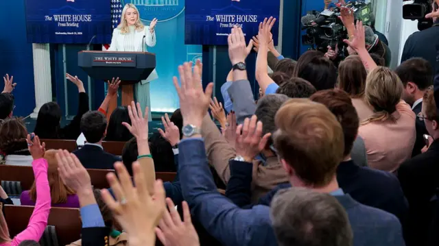 Leavitt faces reporters with hands raised for questions in White House briefing room