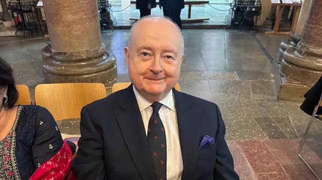 David sits on a chair inside the cathedral