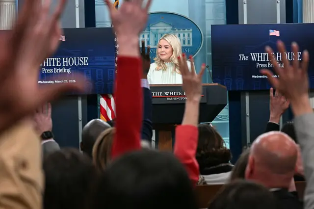 Reporters raise their hands to ask questions of the White House press secretary