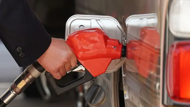 Close view of a red fuel pump used to top up a car a petrol station.