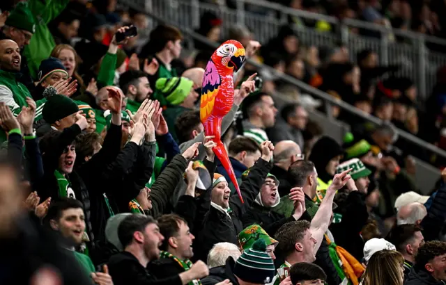 An Ireland fan holds up an inflatable parrott in the away end