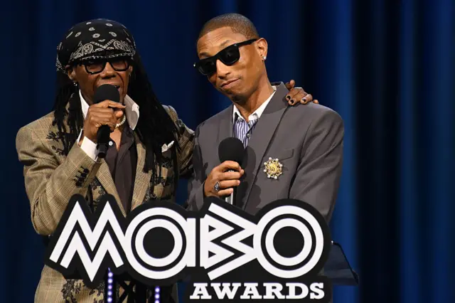 Nile Rodgers with his arm around Pharell Williams