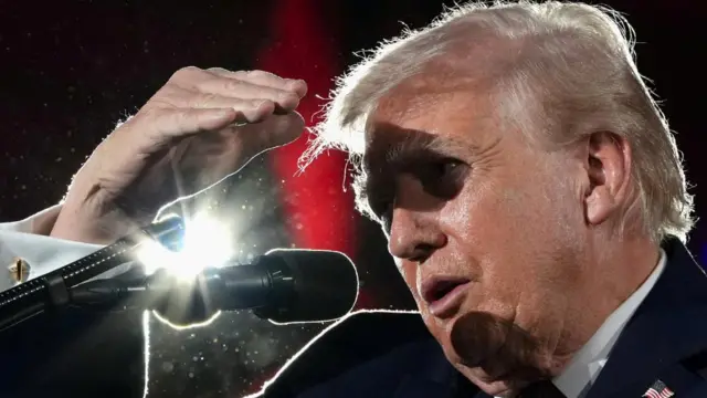 Trump shields his eyes with his hand as he speaks