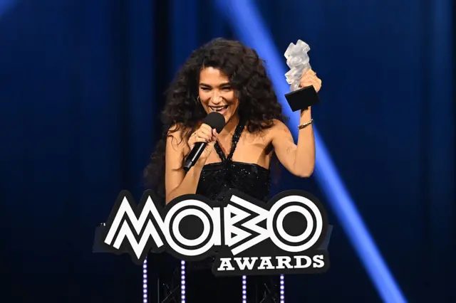 Olivia Dean holding up her Mobo award