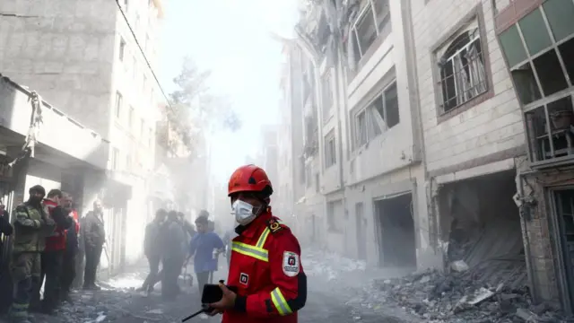 Emergency responders inspect the site of a residential building damaged by a strike in Tehran