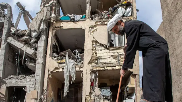 A man sweeps up debris near a residential building that was hit in an airstrike in the early hours of March 27, 2026 in Tehran, Iran.