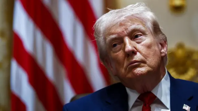 Donald Trump, with the American flag behind, looks to the right