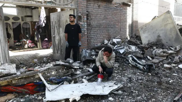 People react at the site of a residential building damaged by a strike in Tehran, Iran