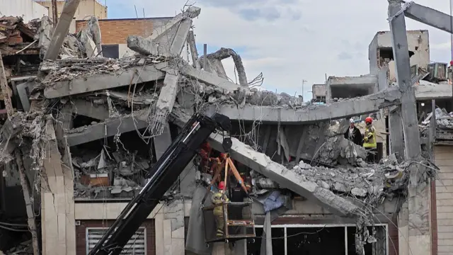 Rescue workers search for bodies in the rubble of a residential building following a hit in an airstrike in the early hours of March 27, 2026 in Tehran, Iran.