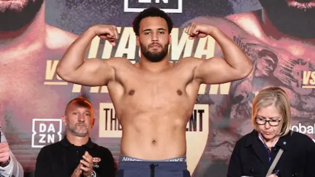 Moses Itauma is shirtless and holding up his arms