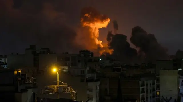 A red glow around a smokey cloud over a city skyline at night time