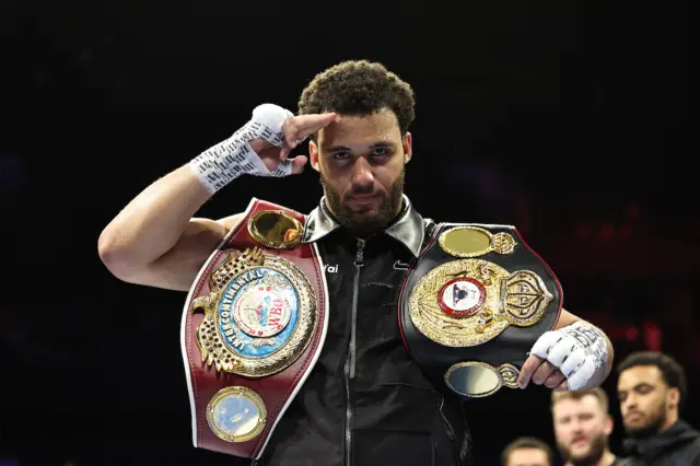 Moses Itauma salutes and holds his titles over his shoulders