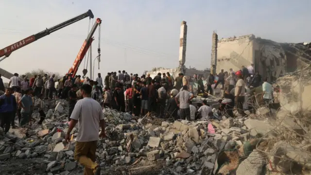 People and rescue forces work following an Israel strike on a school in Minab, Iran,.