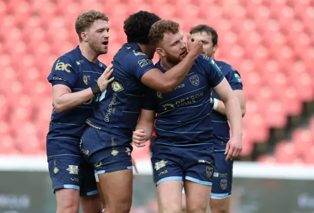 Aneurin Owen of Dragons celebrates with team mates after scoring a try