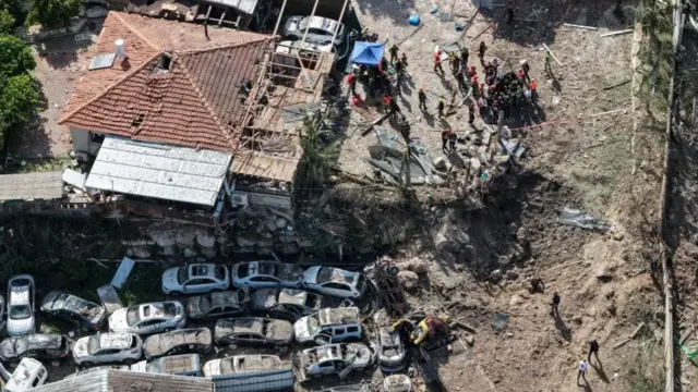 An aerial view of the site of the crater surrounded by cars and a building