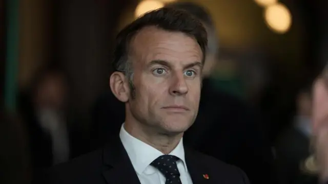 French president Emmanuel Macron looks into distance, wearing suit and patterned tie