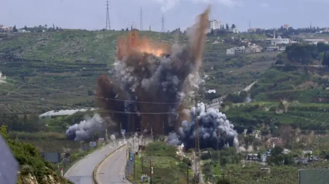 An explosion is seen on a road running through what appears to be farmland