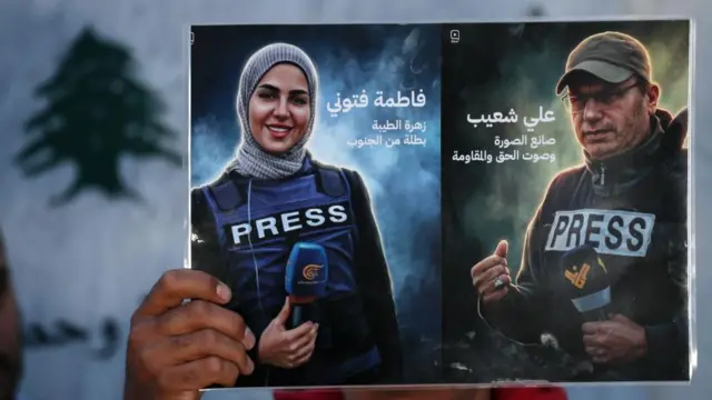 A hand holds up a poster showing  Hezbollah's Al Manar TV correspondent Ali Shoeib (R) and Beirut-based Al Mayadeen TV reporter Fatima Ftouni (L). Both are pictured holding microphones and wearing press vests