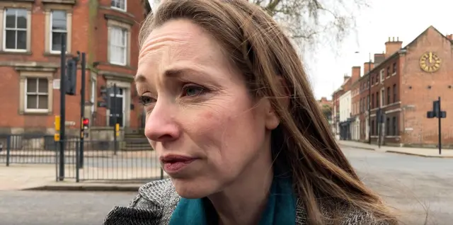 The head and shoulders of Catherine Atkinson, who has shoulder length brown hair and is wearing a grey jacket