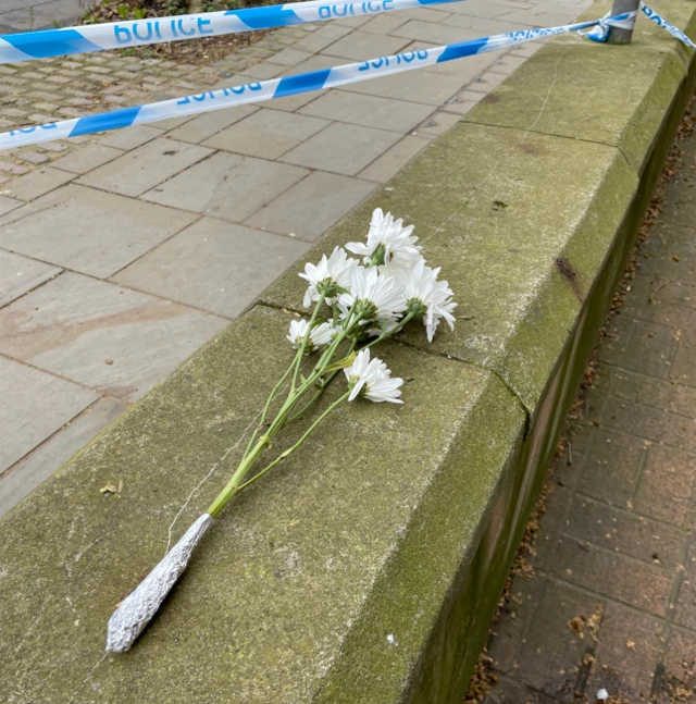 Bunch of white flowers left on a wall outside of a police cordon in Derby