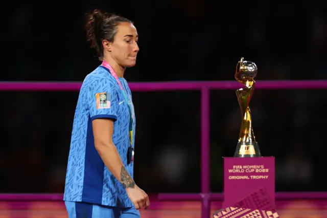 Lucy Bronze of England walks past the trophy