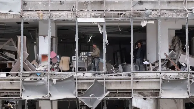 A worker works at the Gandhi Hospital, which is damaged after U.S.-Israeli strikes on a state TV telecommunication tower nearby in Tehran, Iran