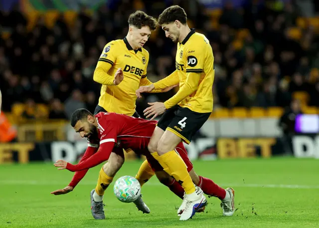Mohamed Salah of Liverpool is challenged by Ladislav Krejci and Santiago Bueno of Wolverhampton Wanderers