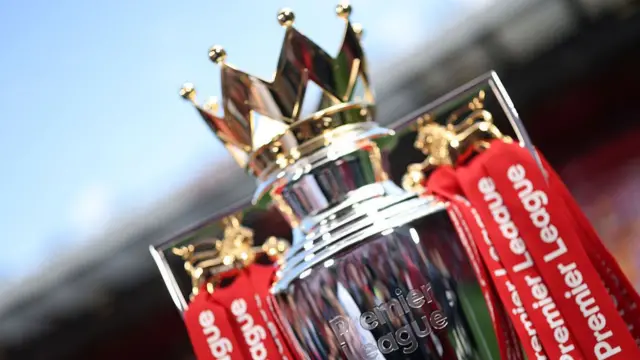 A detailed view of the Premier League trophy, dressed in red ribbons,