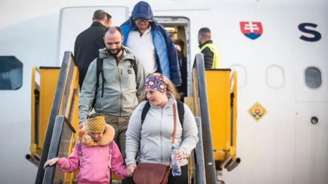 A group of people walk down the steps of a plane