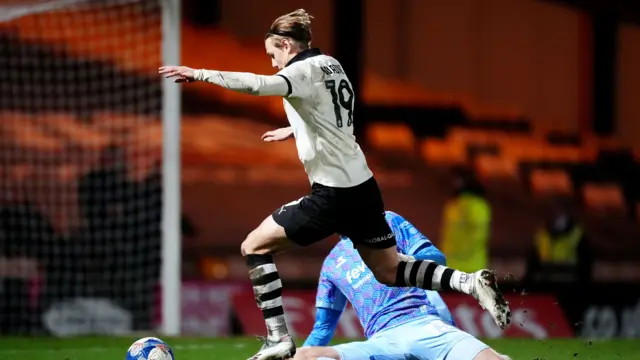 Ben Waine jumps over Joe Lumley with the ball just in front of his feet