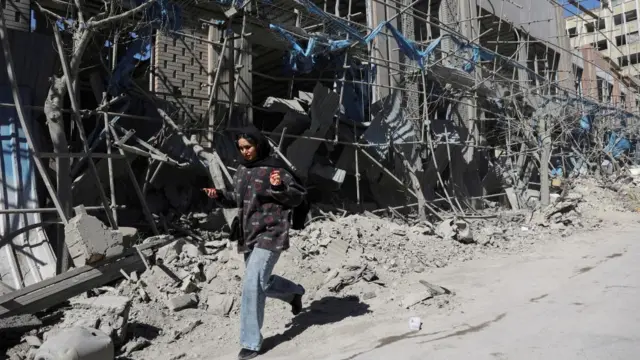 A woman walks next to a completely demolished building