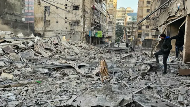 A man walks around the rubble of a destroyed building