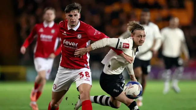 Noah Eile and Ben Waine (right) put an arm on each other in a challenge as the ball floats in front of them