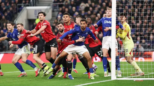 Manchester United and Everton players grapple at a corner