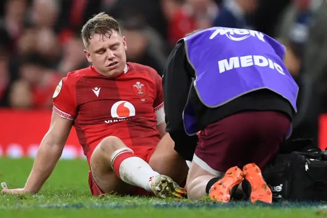 Sam Costelow sits on the pitch in pain and is receiving treatment