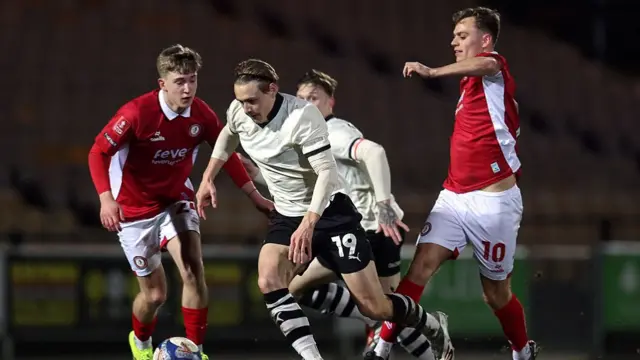 Ben Waine (centre) runs with the ball past Scott Twine (right) who sticks his leg out