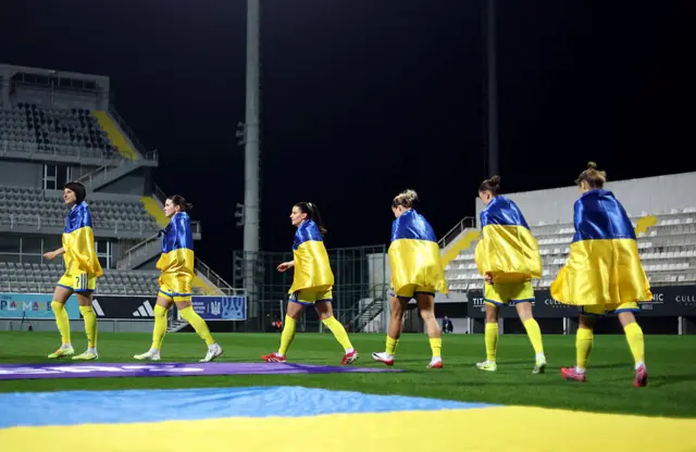 Ukraine players walk out onto the pitch draped in their country's flag prior to the 2027 FIFA Women's World Cup Qualifier between Ukraine and England at Mardan Sports Complex on March 03, 2026.