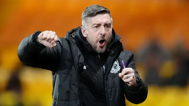 Jon Brady with his mouth open and his right arm up and fist clenched