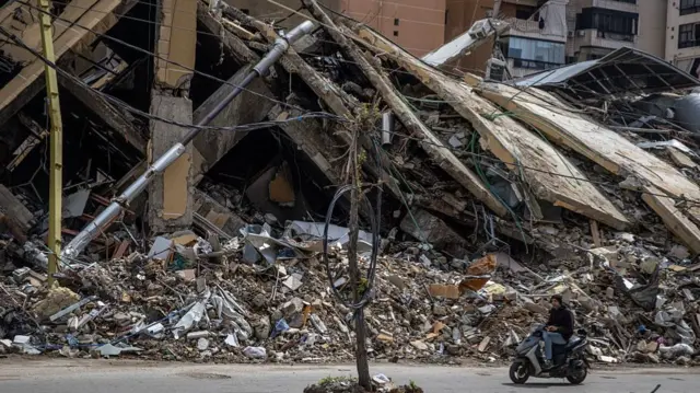 A motorbike passes a destroyed building in southern Beirut on Saturday - Israel has carried out regular airstrikes on the city in the past month