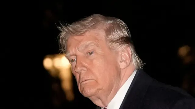 Picture of Donald Trump taken from the right of his face as he looks diagonally into the distance. He wears a black suit, white shirt and has a serious look on his face