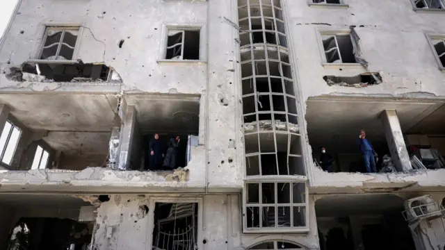 People inspect damage to a residential building after it was hit by a strike