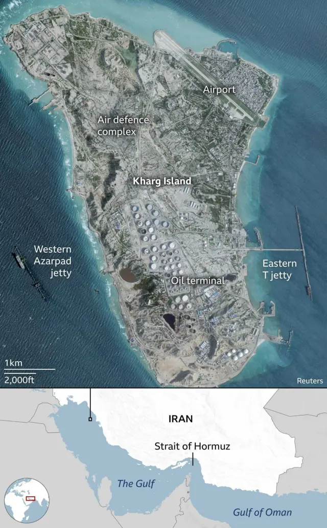 A graphic showing the location of Kharg Island in the northwest of The Gulf about 25 kilometres off the coast of Iran. A satellite image shows the whole island which is roughly eight kilometres long and four kilometres wide. Shadows indicate that the island has many rocky outcrops but the island has been heavily industrialised. There is an airport in the northeast that extends slightly into the sea and around it appears to be the main accommodation on the island. The oil terminal takes up most of the southern half of the island where more than fifty large, white circular structures are clearly visible. These are the oil containers and they are surrounded by other smaller industrial buildings. The south of the island is flanked by two jetties for oil tankers to dock when loading. In the middle of the island an area is labelled as being an air defence complex.