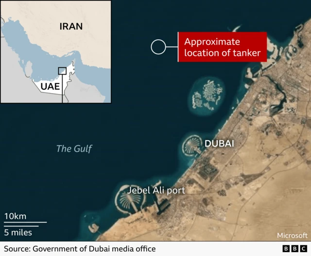 A satellite map showing the coastline of Dubai and the Gulf, with Jebel Ali port labelled to the south west and artificial palm‑shaped peninsulas visible offshore. A red marker labelled Approximate location of tanker sits offshore in the Gulf. An inset map in the upper left shows the UAE and Iran with a box highlighting the Dubai area.