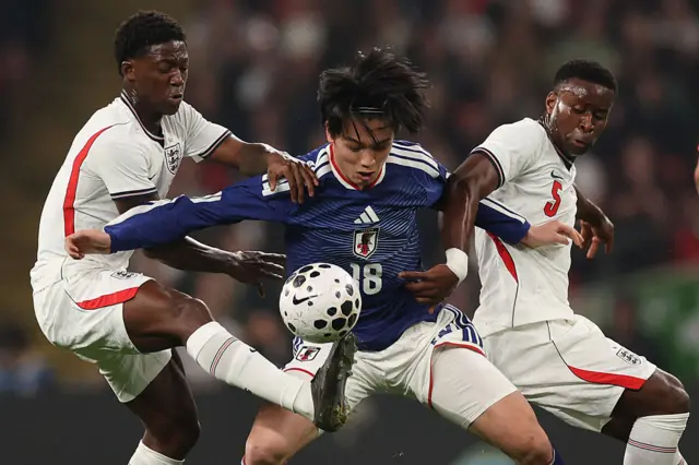 Japan's forward Ayase Ueda (C) vies with England's midfielder Kobbie Mainoo (L) and England's defender Marc Guehi (R) during the friendly international football match between England and Japan at Wembley Stadium in London on March 31, 2026.
